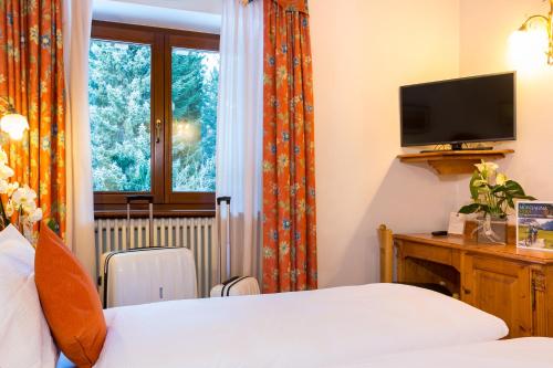 a bedroom with a bed and a tv and a window at Hotel Bonapace ***S in Madonna di Campiglio