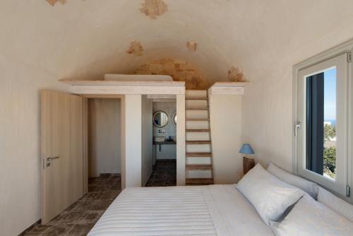 a bedroom with a bed with a ladder and a window at Amaranthine Villa in Imerovigli
