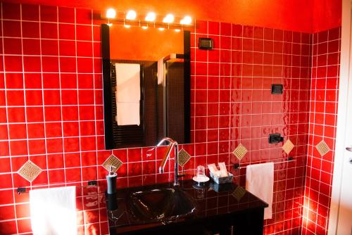 Baño de azulejos rojos con lavabo y espejo en Tenuta La Vigna, en Malgesso