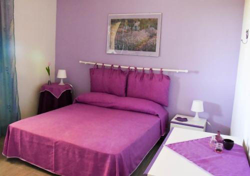 purpurowa sypialnia z łóżkiem z fioletową pościelą w obiekcie Casa Vacanze Portopalo di Capopassero w mieście Portopalo