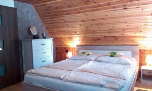 a bedroom with a bed with a wooden wall at Chata Vysočina in Svratouch
