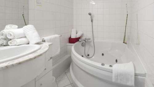 Baño blanco con bañera y lavamanos en Hôtel Restaurant L'Evidence, en Neufchâteau
