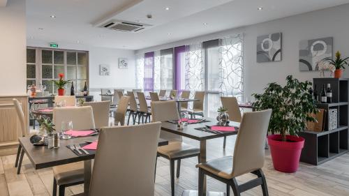 een eetkamer met tafels, stoelen en planten bij Hôtel Restaurant L'Evidence in Neufchâteau