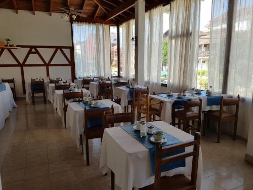 un comedor con mesas, sillas y ventanas en Bariloche en Villa Gesell
