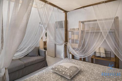 a bedroom with a canopy bed and a couch at Rock Villas - Complex in Emporio Santorini