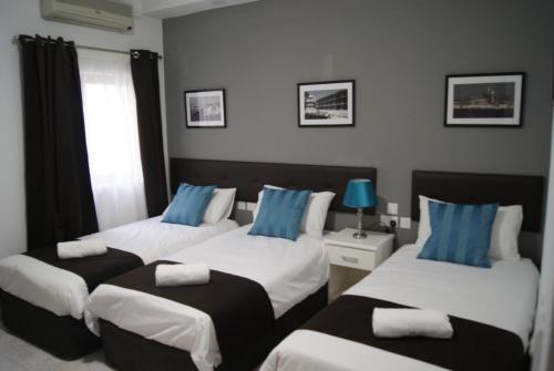 a room with three beds with blue and white pillows at Buccaneers Boutique Guest House in St Paul's Bay