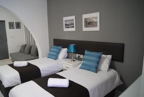 a hotel room with two beds and a couch at Buccaneers Boutique Guest House in St. Paul's Bay