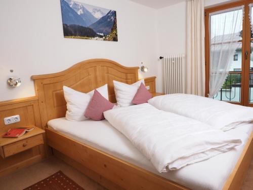 Schlafzimmer mit einem Bett mit weißer Bettwäsche und rosa Kissen in der Unterkunft Haus Antonius in Oberstdorf