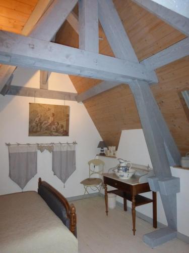Cette chambre mansardée comprend un lit et une table. dans l'établissement Le Manoir sur la Roche, 74, impasse du manoir, 71520 Navour sur Grosne D121, à Clermain