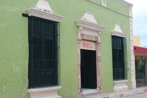 ein grünes Gebäude mit schwarzen Fenstern auf einer Straße in der Unterkunft Hotel Maya Becan in Campeche