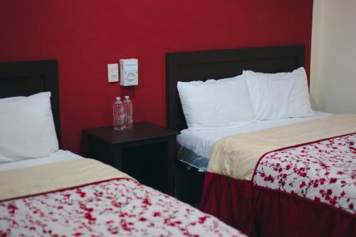 a hotel room with two beds and a red wall at Hotel Maya Becan in Campeche