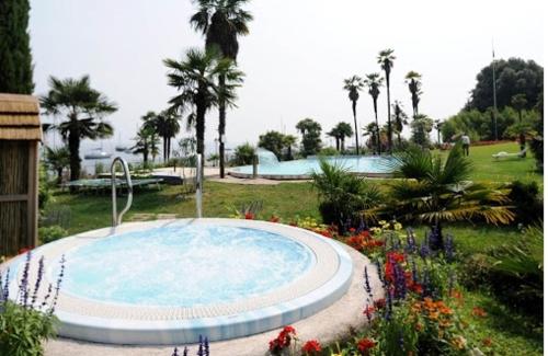 a large swimming pool in a garden with flowers at Hotel Du Parc in Garda