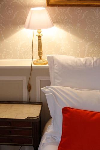 a lamp sitting next to a bed with a red pillow at Les Chambres de Mathilde in Angers