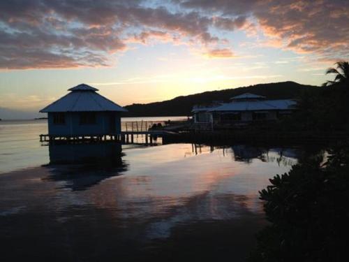 a sunset with two huts on a body of water at Mango Creek Lodge in Port Royal