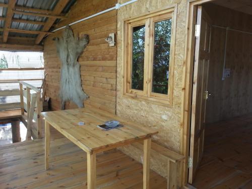 a wooden table in a cabin with a window at Guest House ALUDA in Omalo