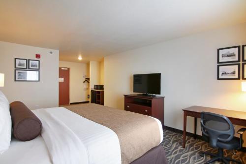 a hotel room with a bed and a desk and a tv at Cobblestone Inn & Suites - Menomonie/UW-Stout in Menomonie