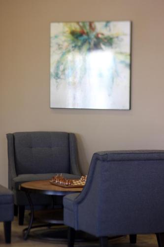 a room with two chairs and a table and a painting at MainStay Suites Fitchburg - Madison in Madison