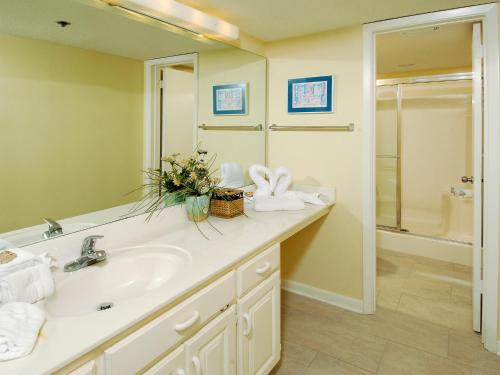 een badkamer met een wastafel, een spiegel en een bad bij Phoenix East Unit 607 in Orange Beach