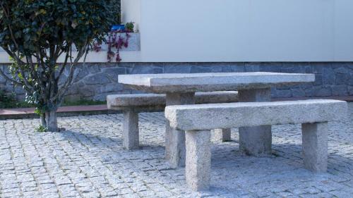 two stone benches sitting next to a tree at Casa das Andorinhas in Ponte de Lima