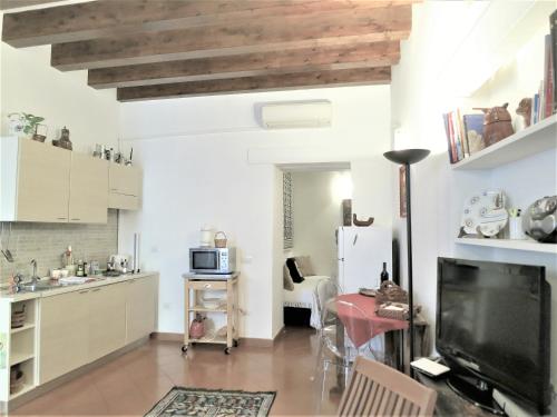 a kitchen with white cabinets and a flat screen tv at La Casa Delle Fate in Siracusa