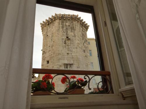 a window view of a tower with flowers on a balcony at Central Square "Stone Pearl Heritage" Luxury Suite in Split