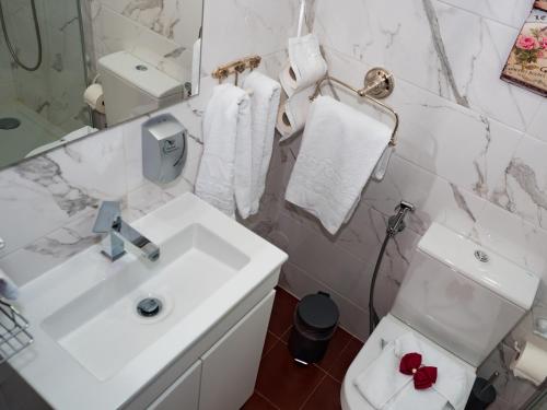a white bathroom with a sink and a toilet at Casa das Andorinhas in Ponte de Lima