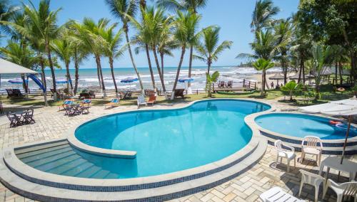 a pool at the beach with palm trees and the ocean at Back Door Village in Olivença