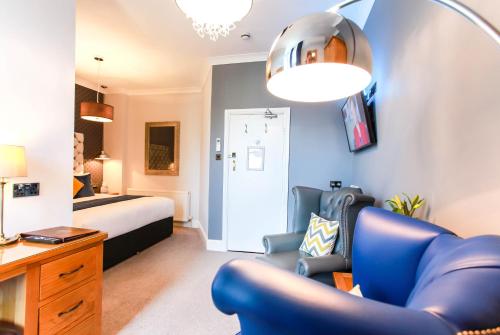a bedroom with a bed and a blue chair in a room at Tyndale B&B Torquay in Torquay