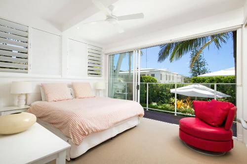 een slaapkamer met een bed, een stoel en een raam bij 1-18 Stevens Street, Sunshine Beach in Noosa Heads