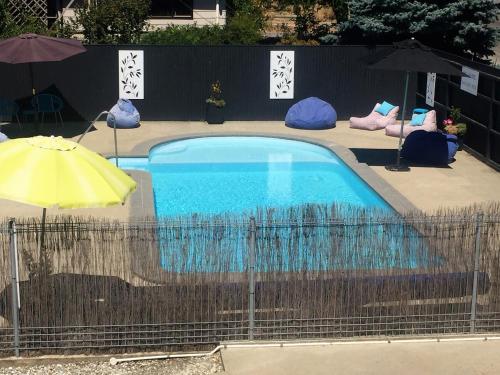 a blue swimming pool with an umbrella and chairs at Fairway Motel & Apartments in Wanaka