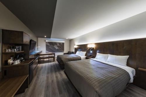 a hotel room with two beds and a television at Hôtel & Suites Normandin Lévis in Lévis