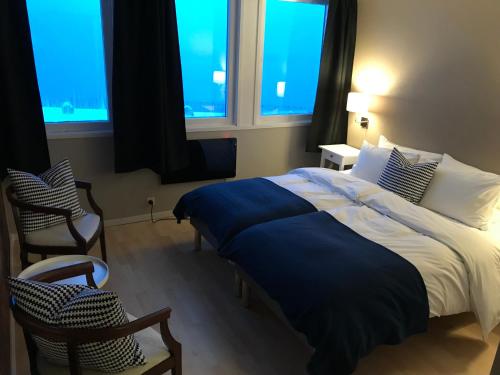 a bedroom with a large bed and two windows at Sogn Hotel in Vadheim