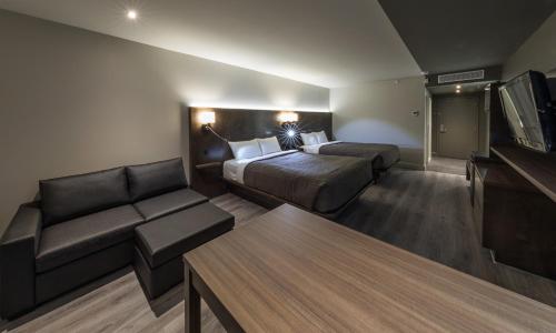 a hotel room with a bed and a couch at Hôtel & Suites Normandin Lévis in Lévis