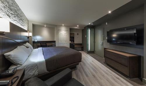 a hotel room with a bed and a flat screen tv at Hôtel & Suites Normandin Lévis in Lévis