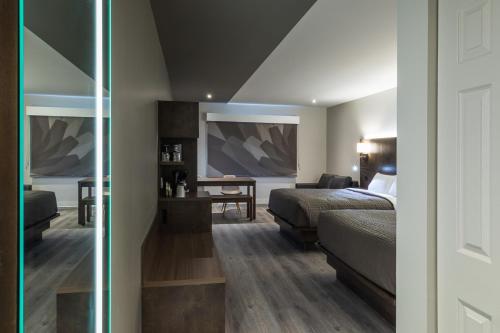 a hotel room with a bed and a desk and a table at Hôtel & Suites Normandin Lévis in Lévis