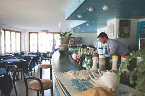 a man standing behind a bar in a restaurant at Hotel Zenith in Cervia