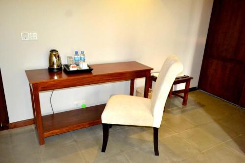 a wooden desk with a white chair and a telephone at Kethaka Aga in Tissamaharama