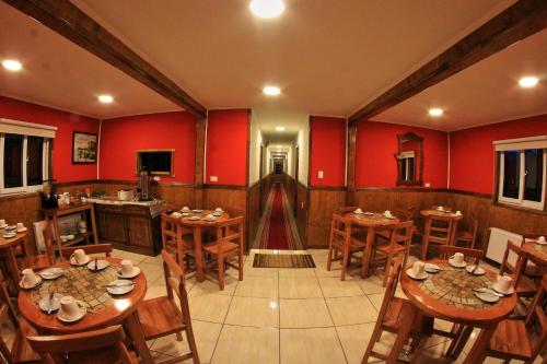 a dining room with red walls and wooden tables and chairs at Hostal America en Puerto Natales in Puerto Natales