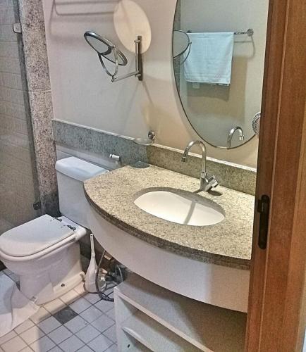 a bathroom with a sink and a toilet and a mirror at Marulhos suítes e resorts in Porto De Galinhas
