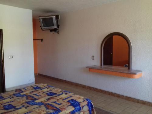 a bedroom with a bed and a mirror and a tv at Promotora Hotelera Tocuila in Texcoco de Mora