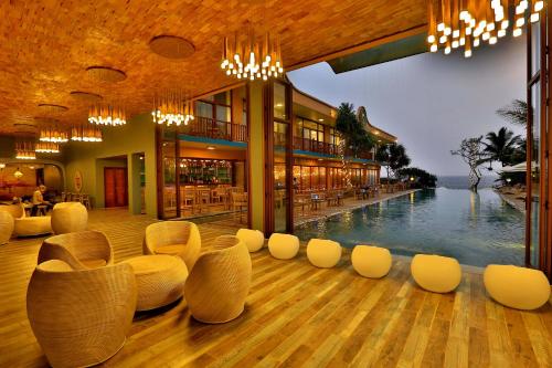 a hotel lobby with a pool and white chairs at Thaproban Pavilion Waves in Unawatuna