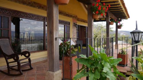 a porch with a chair and a balcony with flowers at Casas La Primavera in Villa de Leyva