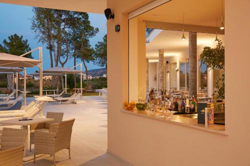 a patio with tables and chairs and a bar at TUI BLUE Tropea in Santa Domenica