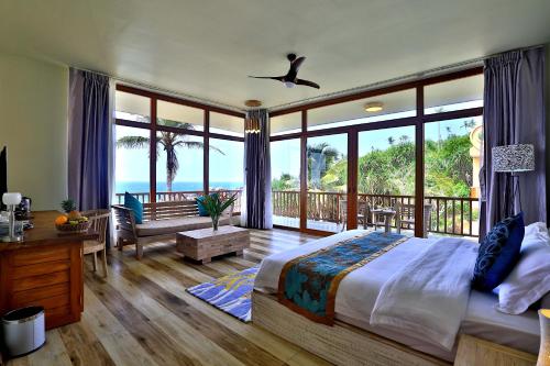 a bedroom with a bed and a balcony with the ocean at Thaproban Pavilion Waves Unawatuna in Unawatuna