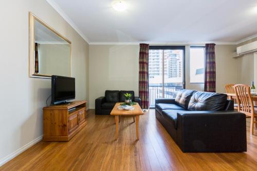 a living room with a couch and a tv at Mont Clare Boutique Apartments in Perth