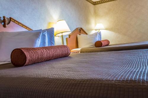 a hotel room with two beds with a red roll on them at Guest House Inn in Junction City