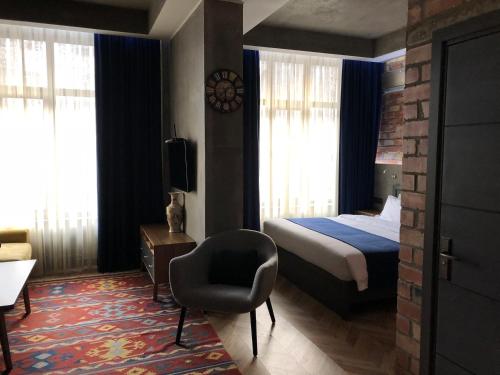 a hotel room with a bed and a chair at Bugu Hotel Bishkek in Bishkek