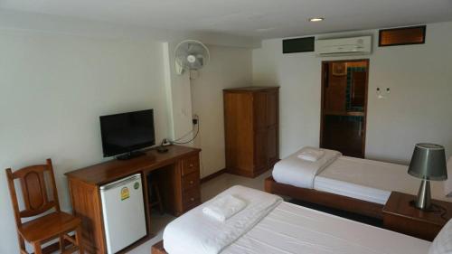 a bedroom with two beds and a tv and a chair at Garden Corner Resort & Hotel in Phitsanulok