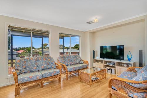 a living room with two couches and a flat screen tv at Green Reef Beach House - Aldinga Beach - C21 SouthCoast Holidays in Aldinga Beach