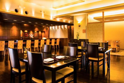 a restaurant with black tables and chairs and a bar at Hotel Hanshin Osaka in Osaka